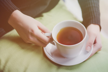 Young woman drinking tea in the morning while looking through the window