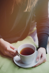 Young woman drinking tea in the morning while looking through the window