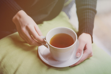 Young woman drinking tea in the morning while looking through the window