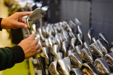 Photo sur Aluminium Golf Personne tenant avec un club de golf à la main dans une boutique de golf