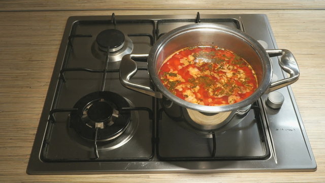 Steel pan with beet soup is on the stove. Preparing borsch