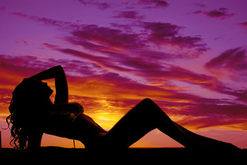 Silhouette of a woman in a bikini laying back in sunset