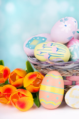 Fototapeta na wymiar Colorful Easter Eggs and Basket With Tulips on a Bright Background