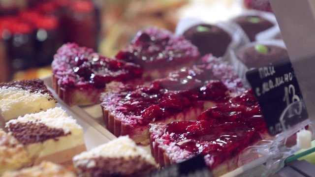 Show window in a grocery shop or a bakery. Tasty and delicious  potato cakes, tarts with strawbery, cream,  jelly finishing, red currants and icing shugar.