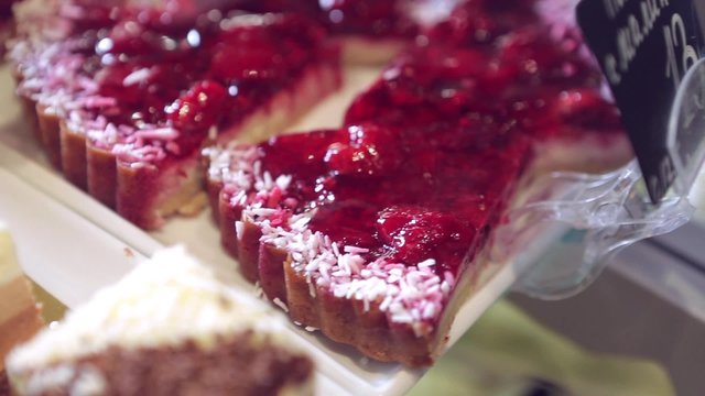 Show window in a grocery shop or a bakery. Tasty and delicious  potato cakes, tarts with strawbery, cream,  jelly finishing, red currants and icing shugar.