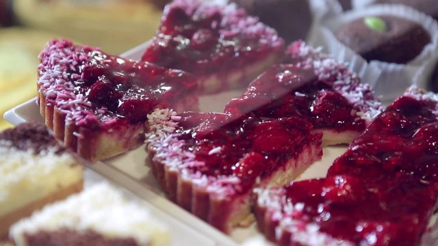 Show window in a grocery shop or a bakery. Tasty and delicious  potato cakes, tarts with strawbery, cream,  jelly finishing, red currants and icing shugar.