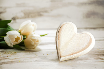 heart of wood and tulips on a white wooden background, love concept