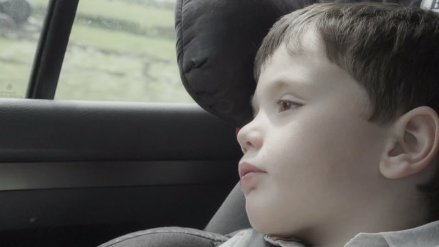 Closeup shot of a little boy traveling in a car with a booster seat