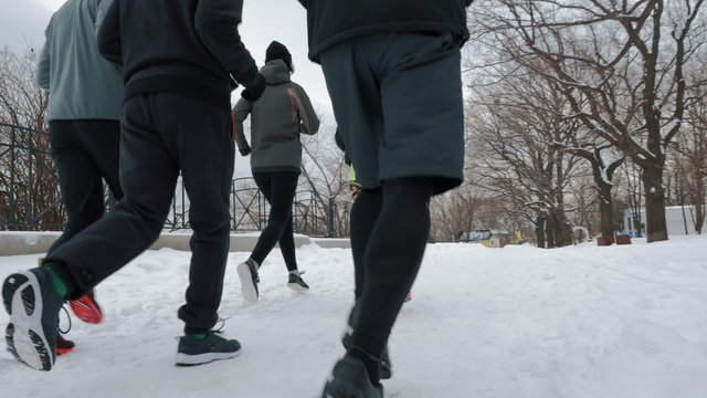 Group of people running on the snow alley, slow motion