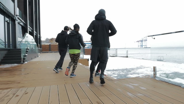 Group of people running on the snow sea berth, slow motion