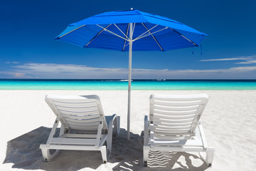 Caribbean beach with blue sun umbrellas and white beds