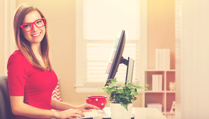 Happy young woman on her computer in her home office