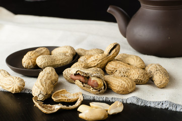 Close up peanuts in shell and peeled on a table with clay teapot