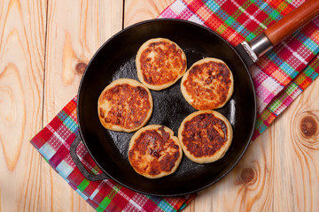 Beautiful golden cheese pancakes fried in a pan. Syrniki.