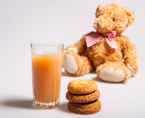 Breakfast for children from Cookies, glass of juice and a toy bear