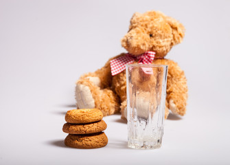 A stack of biscuits, a glass of milk, a toy bear