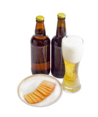 Glass and two bottles of beer, cheese on light background
