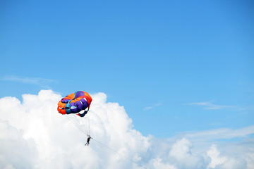 Parasailing man against cumulus clouds and a blue sky