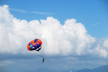 Parasailing man against cumulus clouds and a blue sky