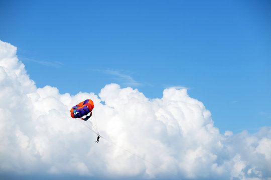 Parasailing man against cumulus clouds and a blue sky