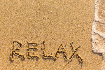  Relax - word drawn on the sand beach with the soft wave.