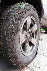 Extremely dirty SUV wheel after driving heavy off-road in the ra
