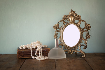 Antique blank Victorian style frame and old book with vintage pearl necklace on wooden table. retro...
