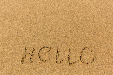 Hello - word drawn on the sand beach. Background, texture of the sand.