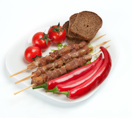 Shish kebab with herbs on a white plate