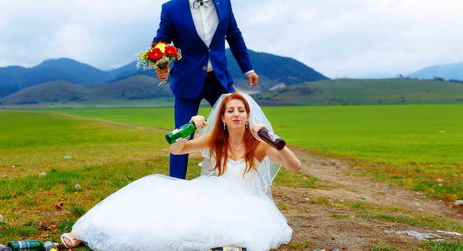 drunken bride with lots of empty beer bottles in mountain landscape  and groom comming to her- funny wedding concept.