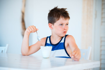 Smiling little boy refuses to eat delicious yogurt