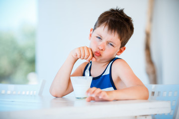 Smiling little boy refuses to eat delicious yogurt