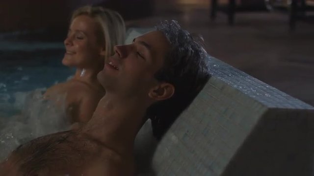 Man and woman are relaxing in the pool on the jacuzzi hot tub plate in spa wellness center. Shot on RED Cinema Camera.