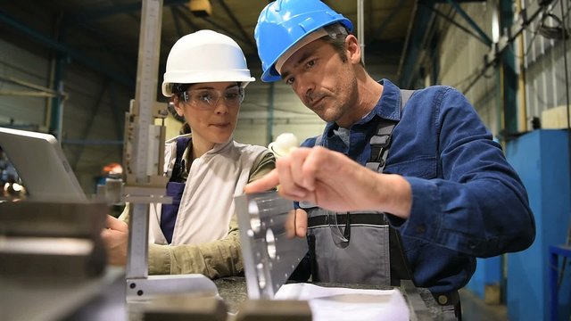 Engineer manager checking conformity with metal worker