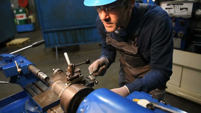 Metal worker using machine in workshop