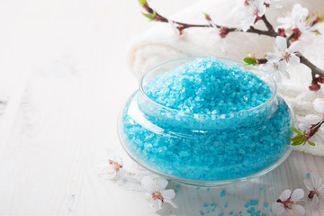 Mineral bath salts, towels and flowers on the  wooden table. Shallow DOF. Focus on the salt.