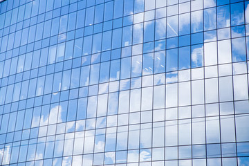 Fototapeta na wymiar Window of a big office building. Blue sky and fluffy white clouds reflected in the windows of modern skyscraper. 