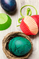 green hand-painted easter egg indise nest with easter eggs backg