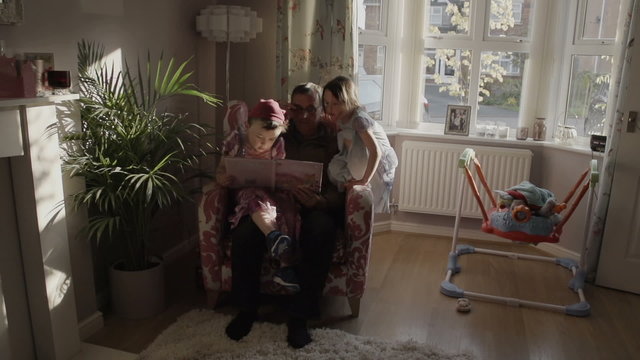A granddad is reading a story book to his  grandson. The grandson is dressed up as a princess from the story in the gender blender style. Shot in super slow motion at 240fps