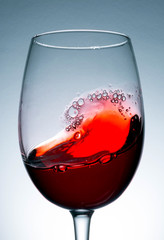 red wine in glass, splashing, splash, wave of red wine close up
