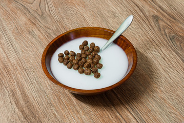 Heart shaped cereal chocolate balls in wooden bowl with milk
