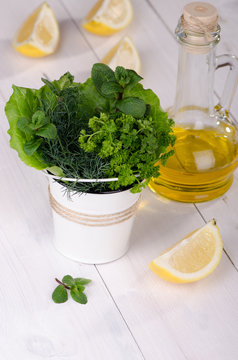 Fresh herbs in a bucket with lemon and olive oil