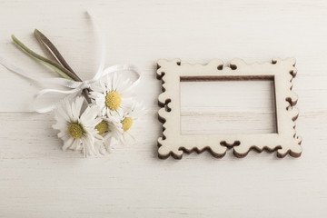 daisy flowers and an empty frame on wooden background