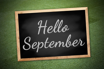Obraz premium Hello Septemberconcept on chalk board and green field background