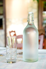 bottle of water and a glass on a table in a restaurant