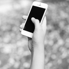 Woman hand holding smartphone against on background black and wh