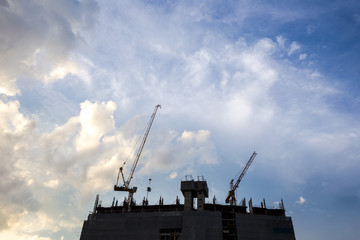 Silhouette construction crane on blue sky.