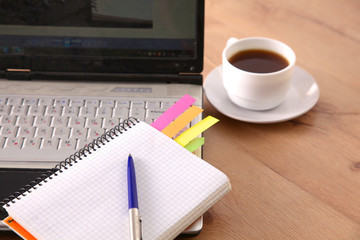 Office table with blank notepad and laptop 