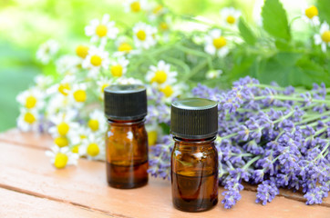 essential oils with herbal flowers on wooden table
