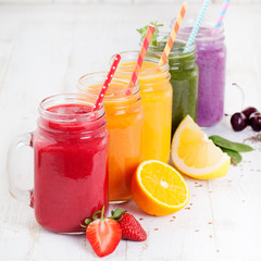 Smoothies, juices, beverages, drinks variety with fresh fruits and berries on a white wooden background.